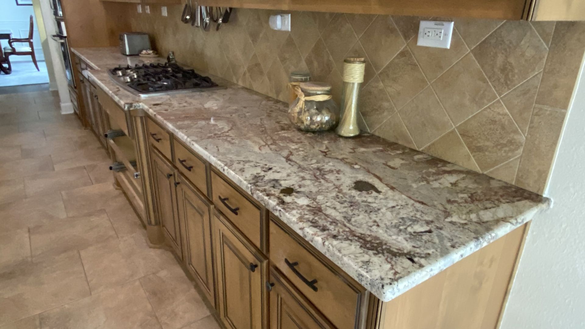Kitchen with brown cabinets, granite countertops, tile backsplash, and appliances.