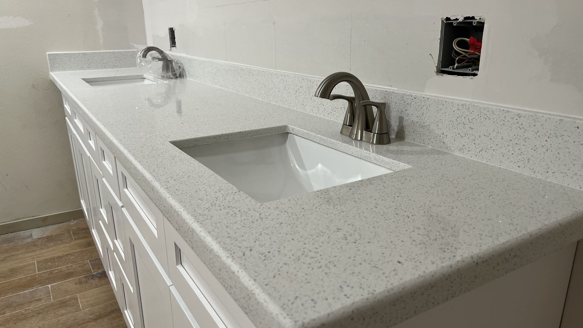 Double sink bathroom vanity with white cabinets, speckled countertop, and silver faucets.