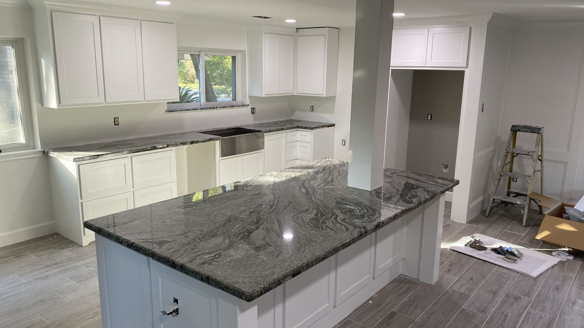 Kitchen with white cabinets, gray granite countertops, and an island.