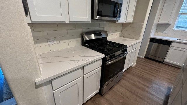 A kitchen with stainless steel appliances and white cabinets.