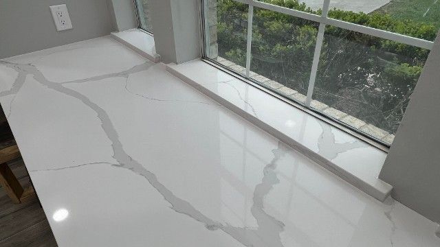A white counter top next to a window in a kitchen.