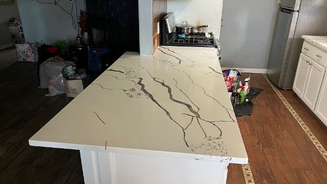 A kitchen with a large white counter top and a stove top oven.
