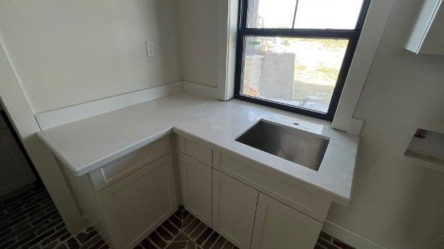 A kitchen with white cabinets and a sink under a window.