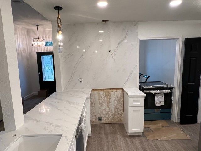 A kitchen with white cabinets , a sink , and a stove.