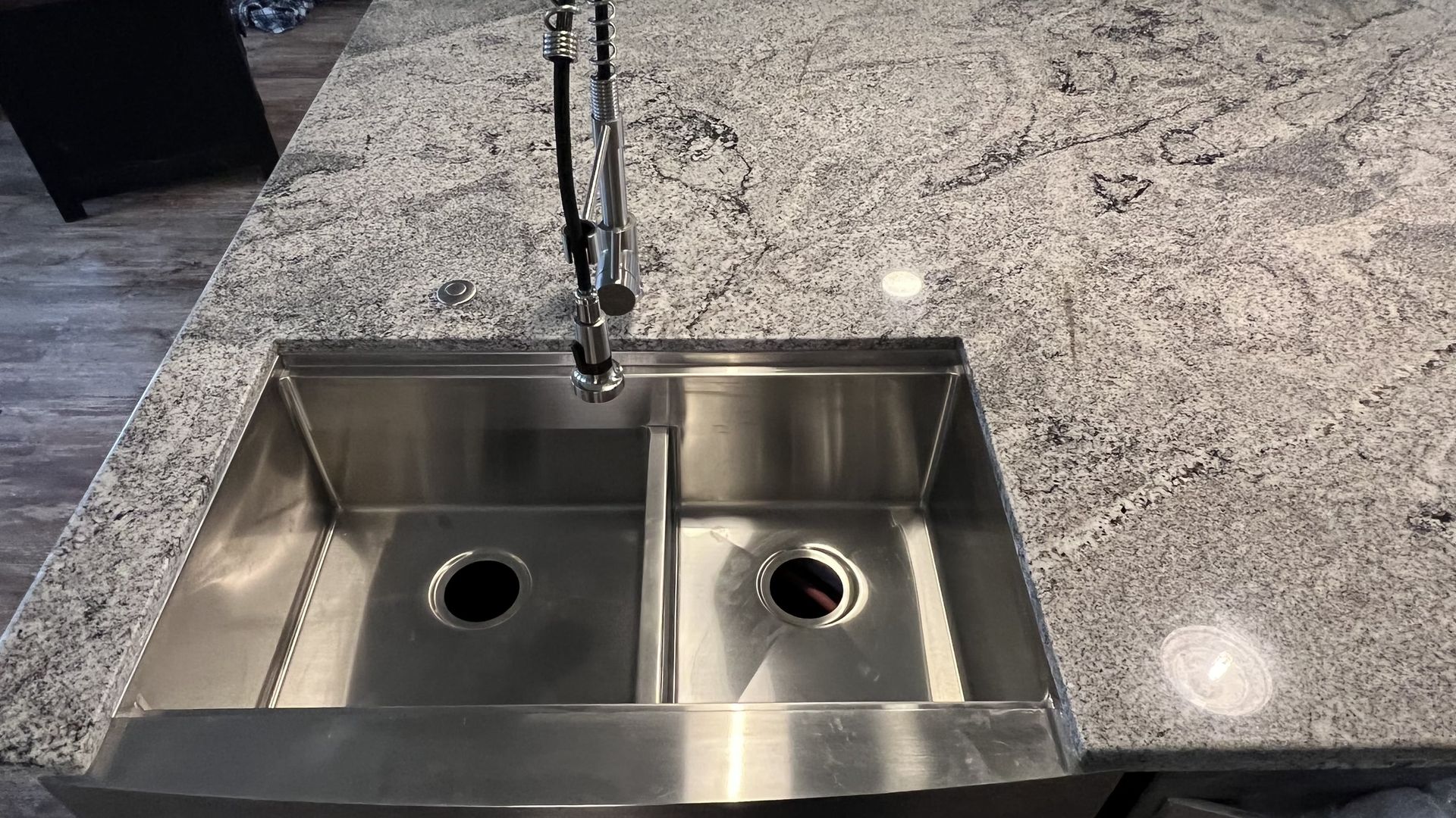 Stainless steel double sink in a granite countertop. A faucet is installed above the sink.