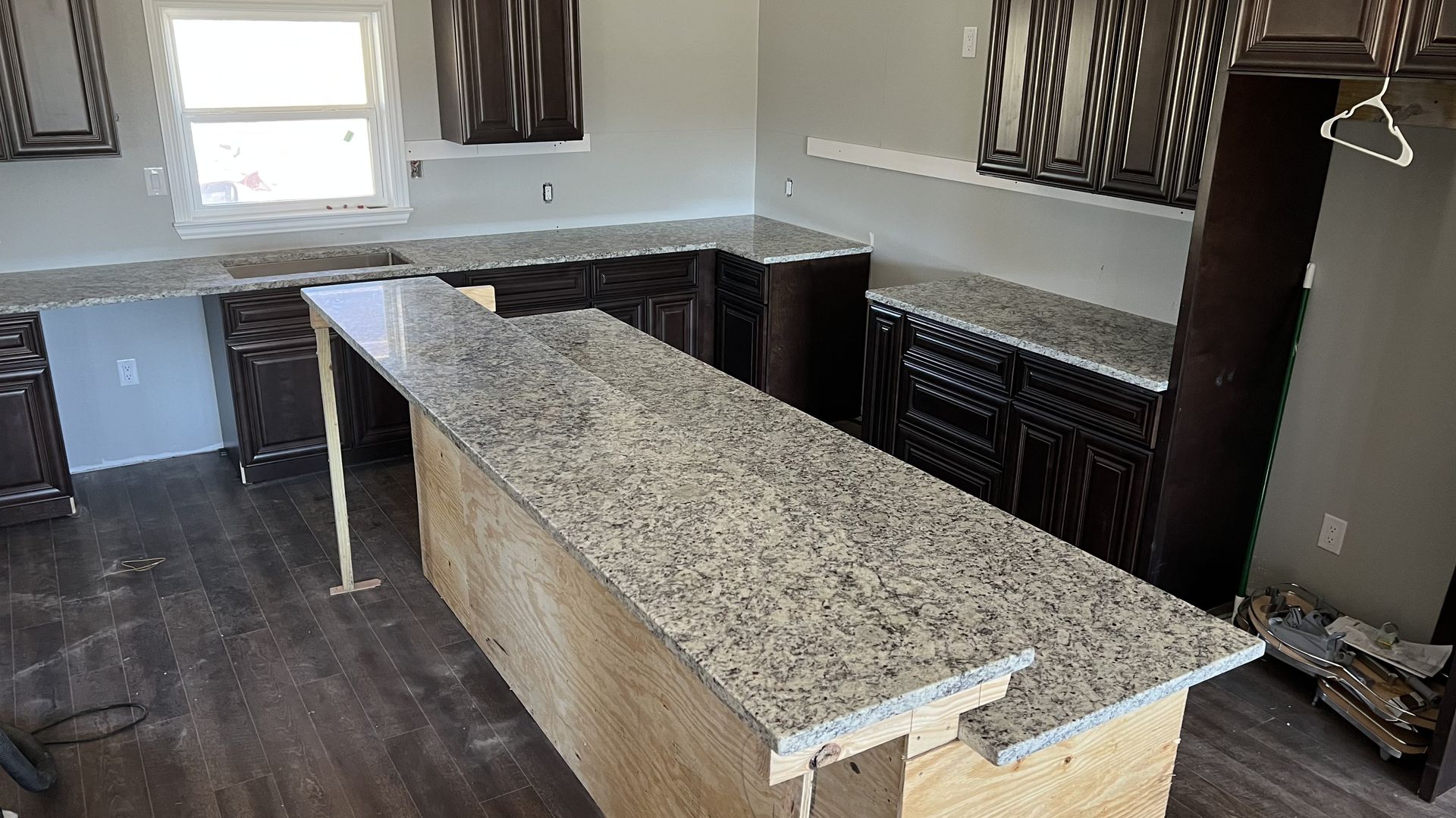Kitchen with dark cabinets, light countertops, and an island. Gray walls and wood flooring.