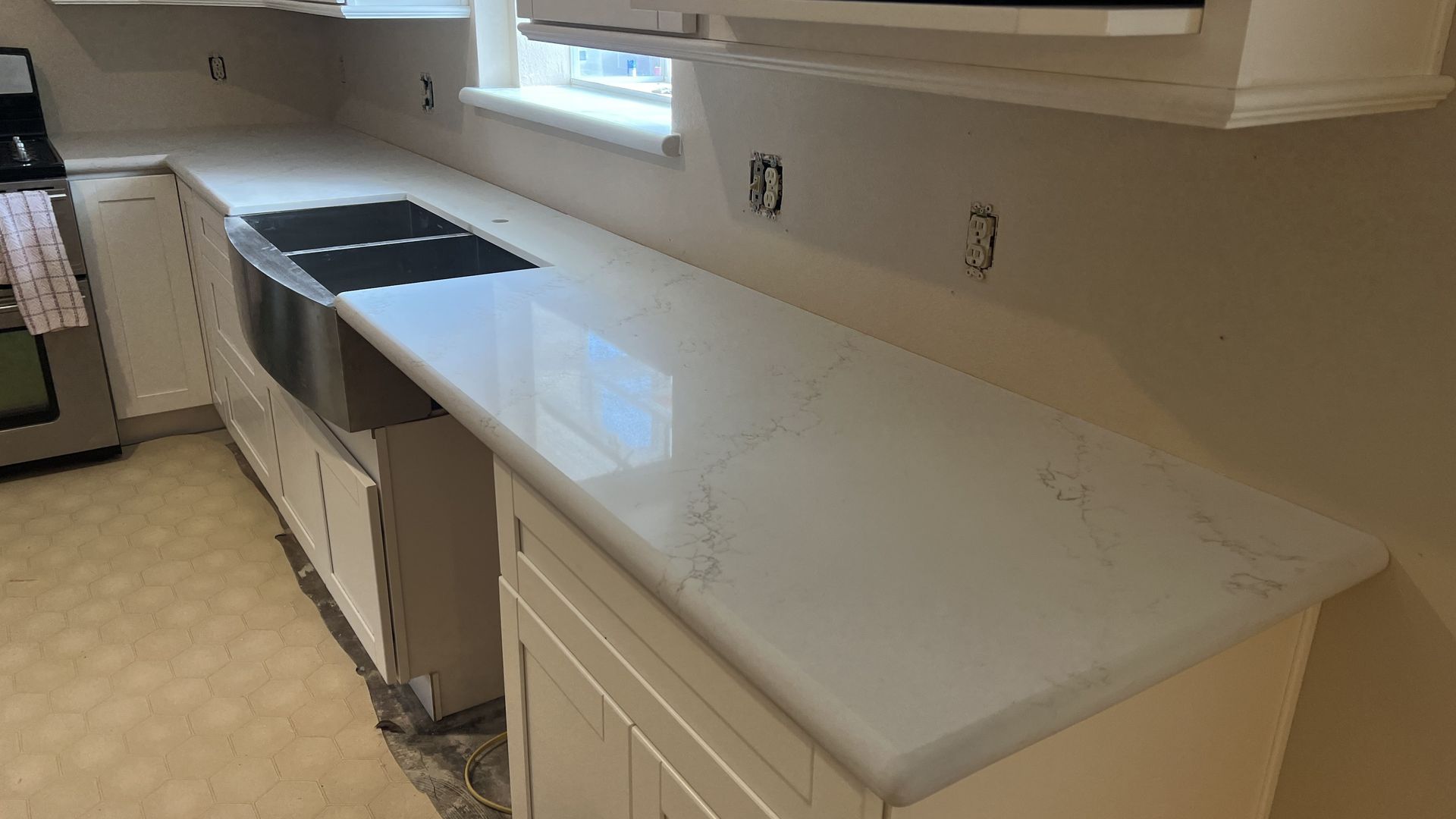 Kitchen with white cabinets, light countertop, and stainless steel sink.
