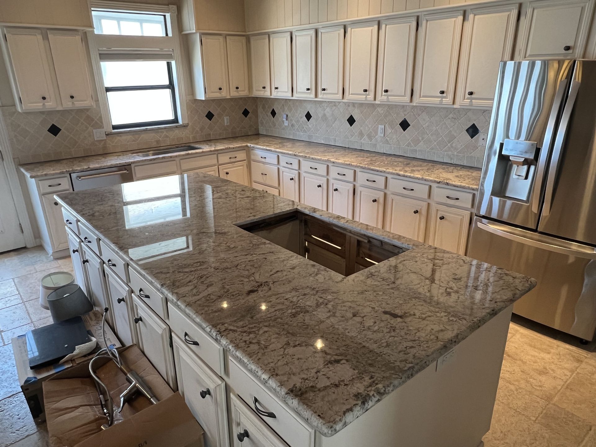 Kitchen with cream cabinets, granite countertops, and stainless steel refrigerator.