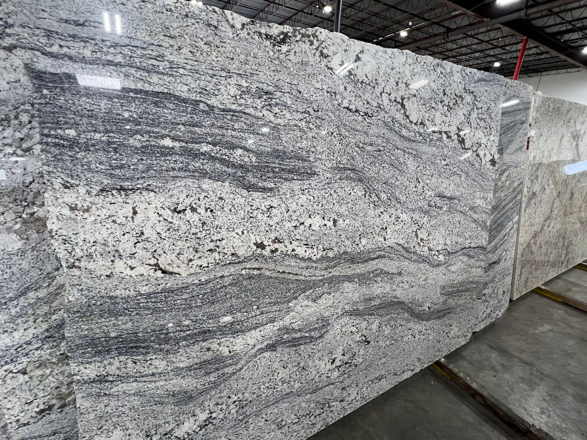 A large white granite slab is sitting on top of a concrete floor in a warehouse.