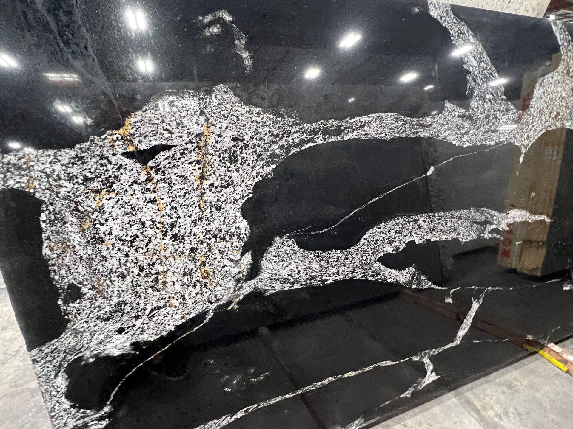 A black and white granite slab is sitting on a concrete floor.
