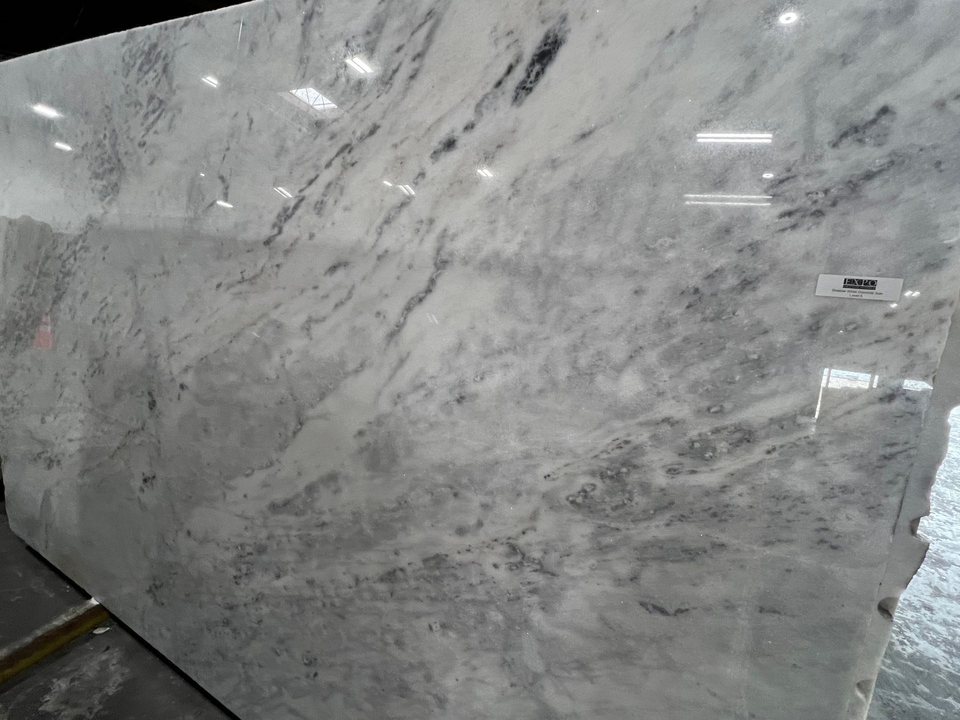 A large white quartzite slab is sitting on top of a concrete floor.