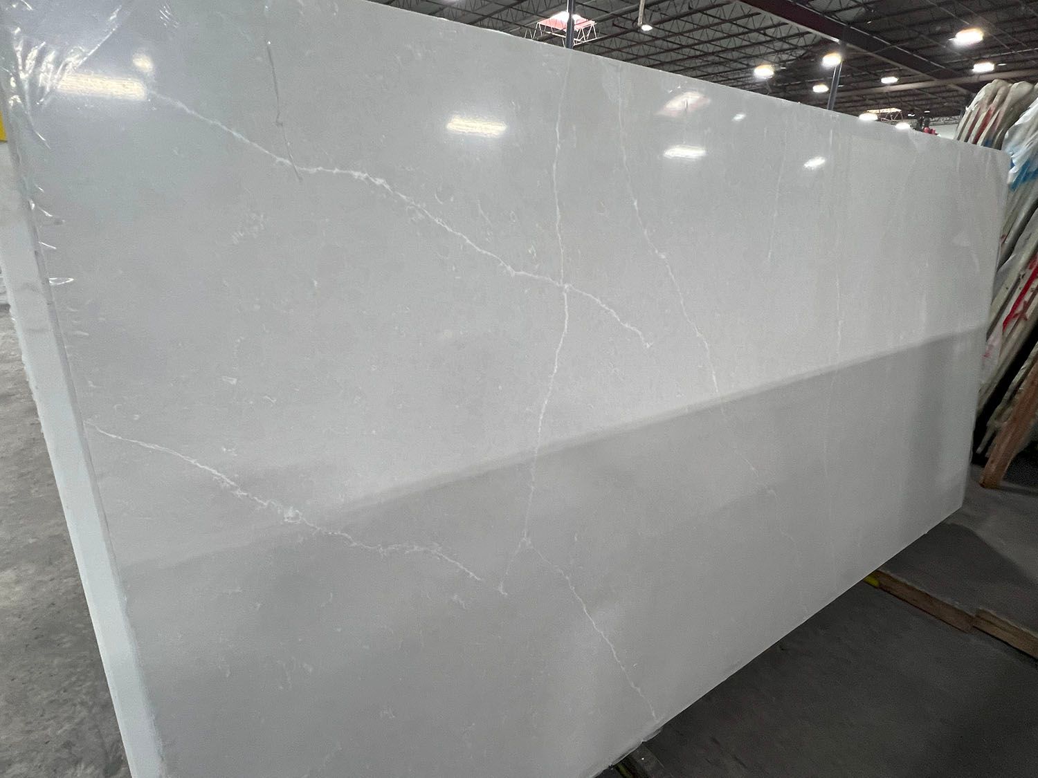 A large white granite slab is sitting on top of a concrete floor in a warehouse.