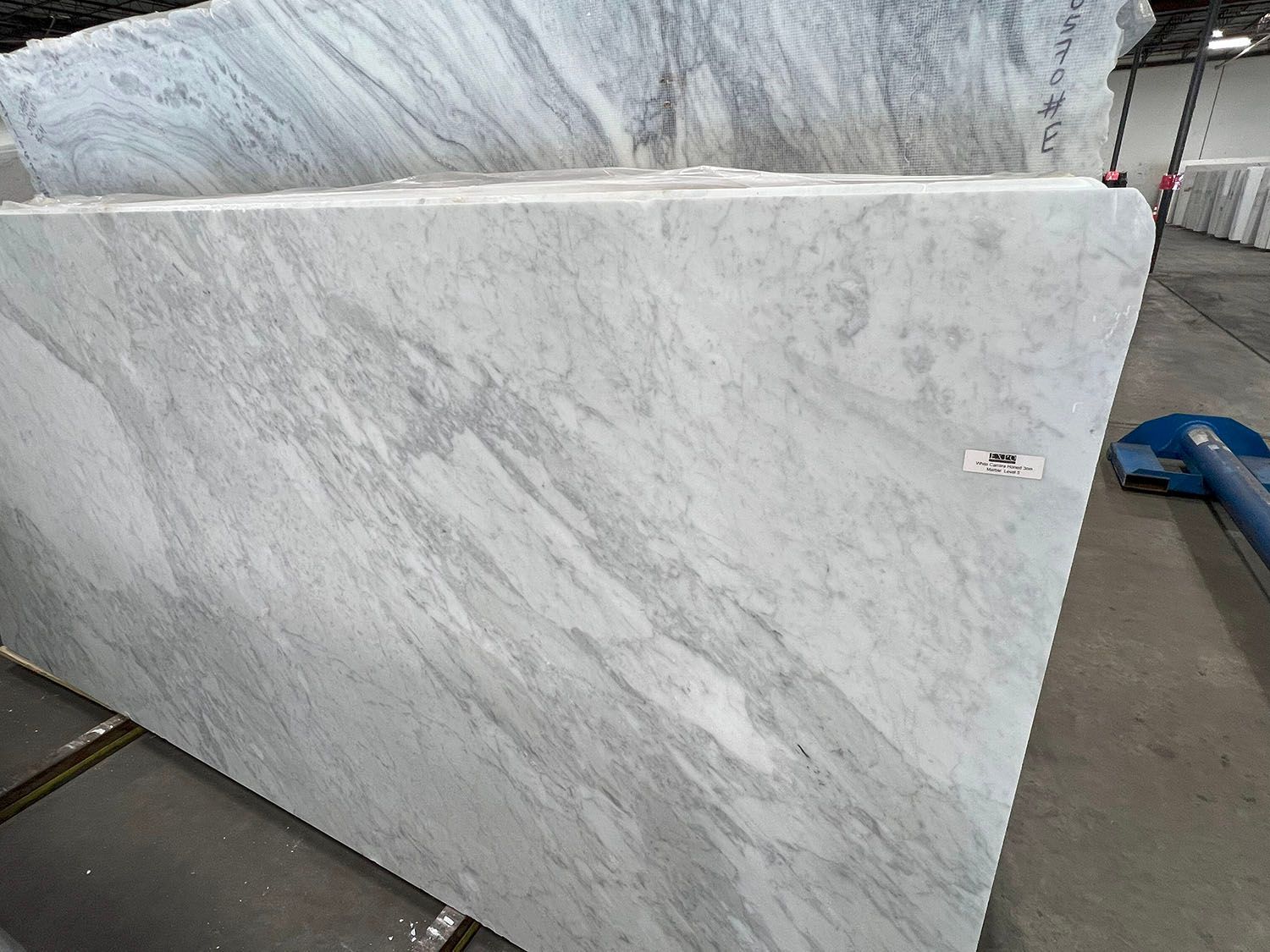 Large slab of white and gray marble, in a warehouse setting.