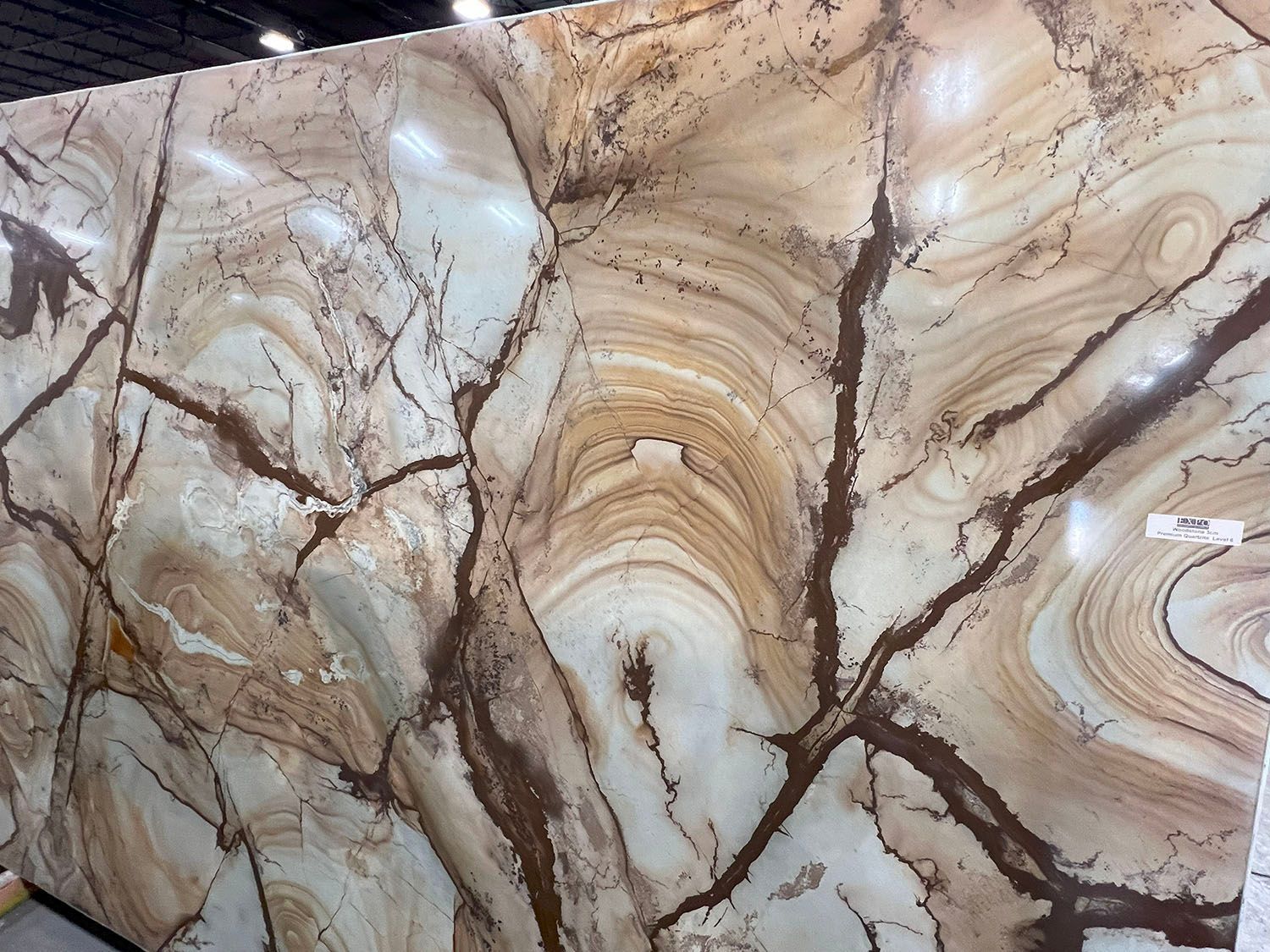 Large polished stone slab with brown and tan swirling patterns and dark brown veining.
