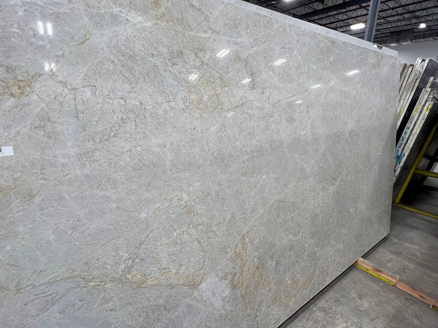 Large slab of beige and gold granite, with visible veining, in a warehouse setting.