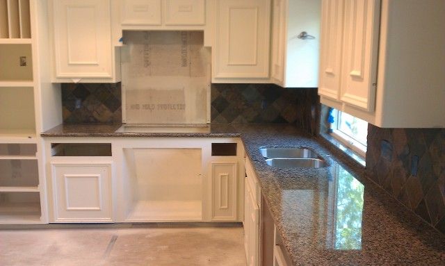 Kitchen with white cabinets, dark countertops, and a double sink.