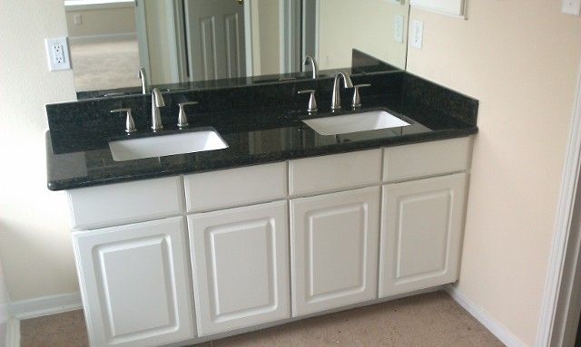 White double vanity with black countertop and two sinks.