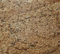 Golden-brown granite countertop with textured surface and dark mineral flecks.