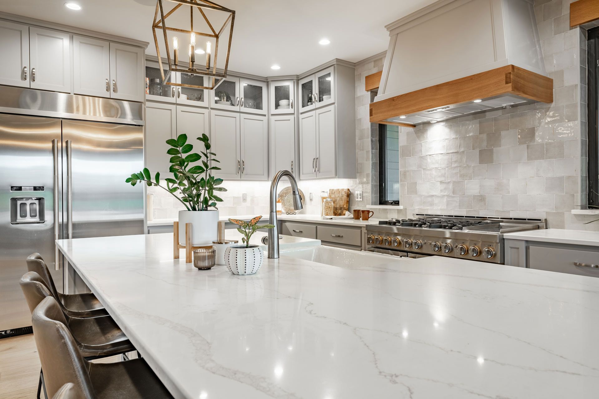 Bright modern kitchen with white island, stainless appliances, marble counters, and pendant lights
