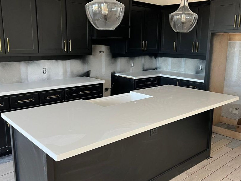 Modern kitchen with white island, black cabinets, and pendant lights