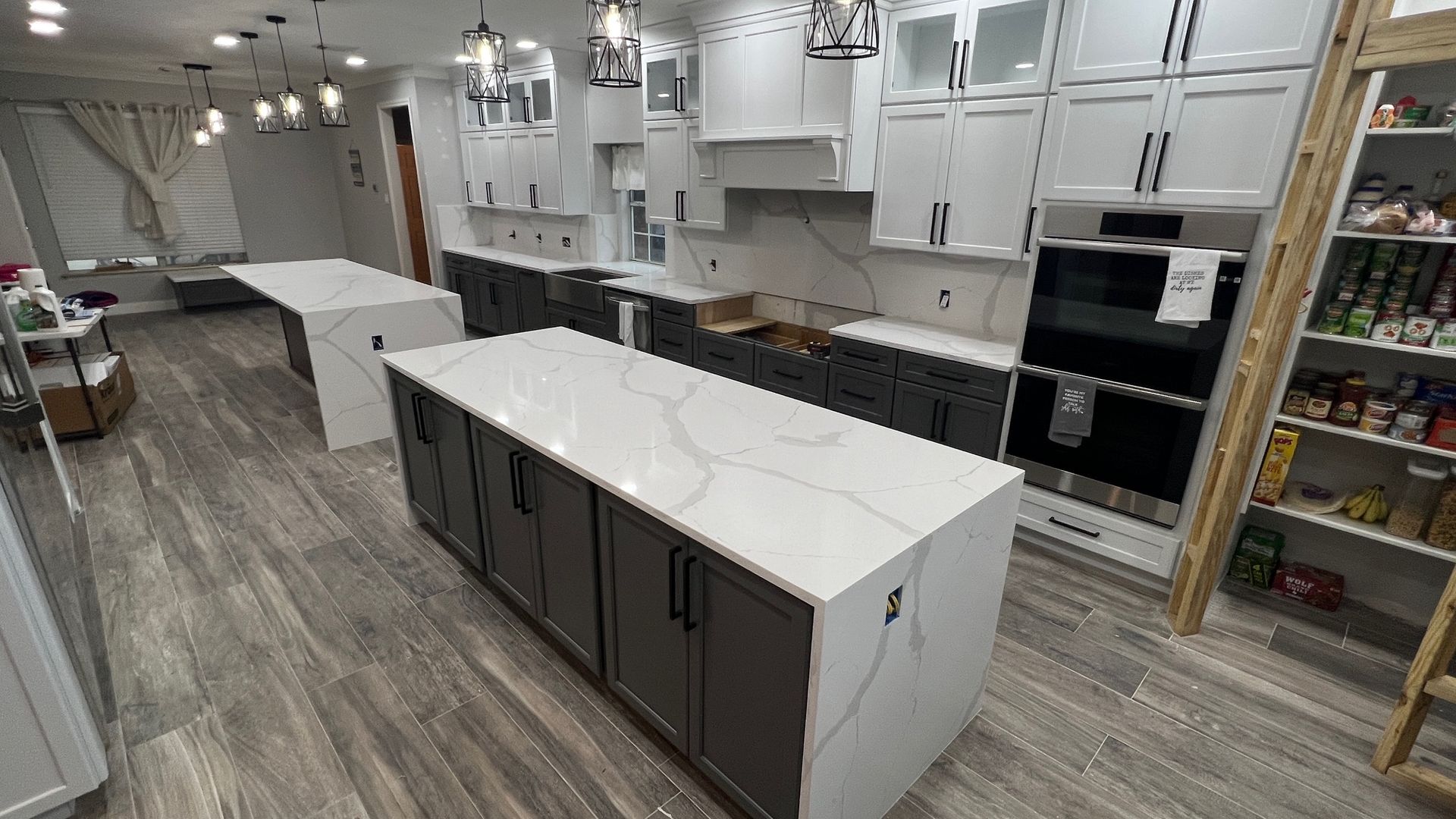 Kitchen renovation with white and gray cabinets, large island, and quartz countertops.