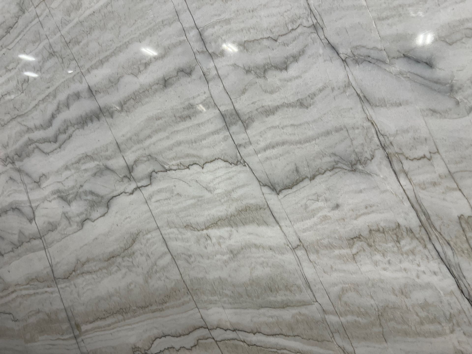 White and gray marble slab with layered patterns and dark veining.