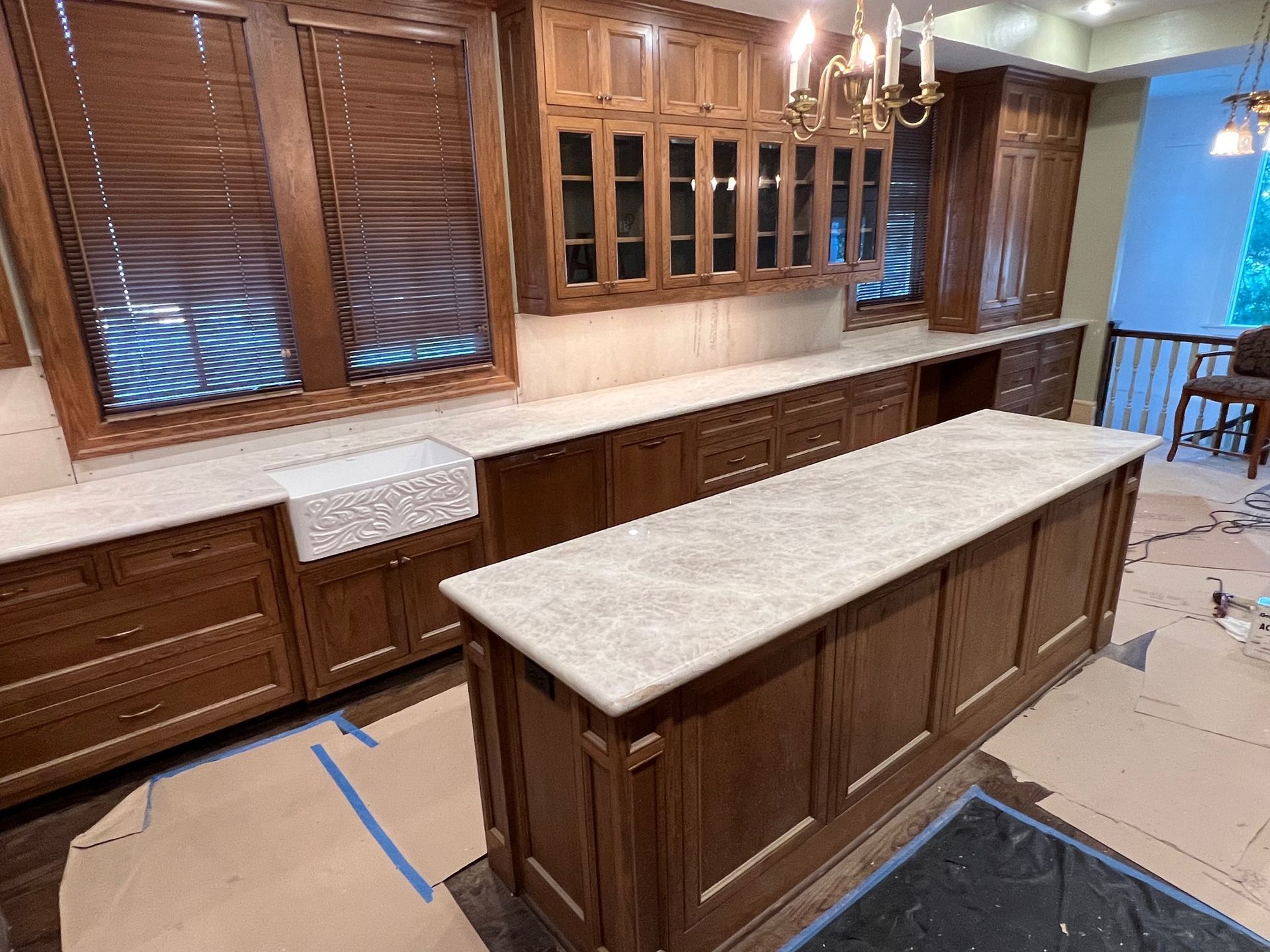 Wood-paneled kitchen with a large island, cream countertops, and built-in cabinets under construction