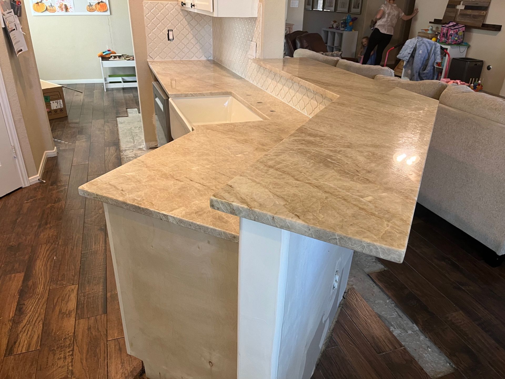 Light wood kitchen island with a white base in an open living area, near a sofa and dining table.