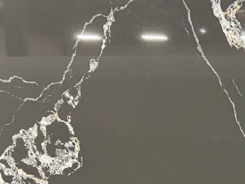 A spacious kitchen featuring white cabinets, a large granite island with bar stools, stainless appliances, and wood floors.