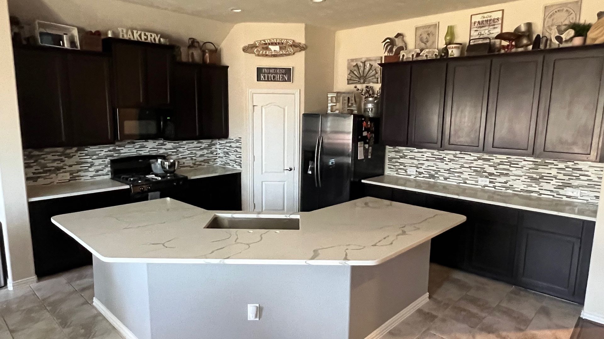 Modern kitchen with dark cabinets, light countertops, and a large island centerpiece