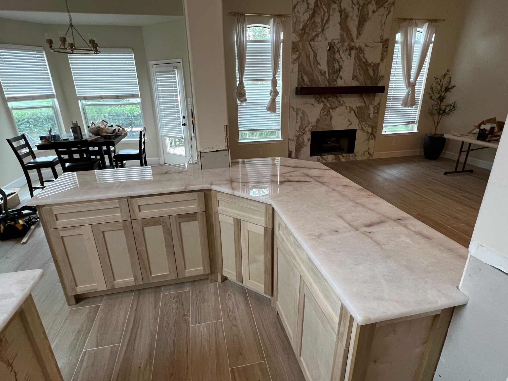 Modern kitchen with light wood cabinets and a large marble island in an open living space
