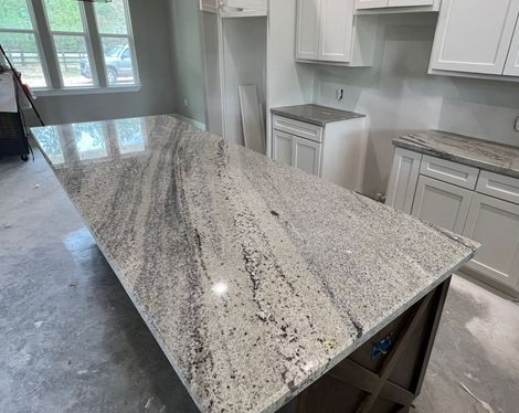 Modern kitchen with a large speckled granite island countertop and white cabinets