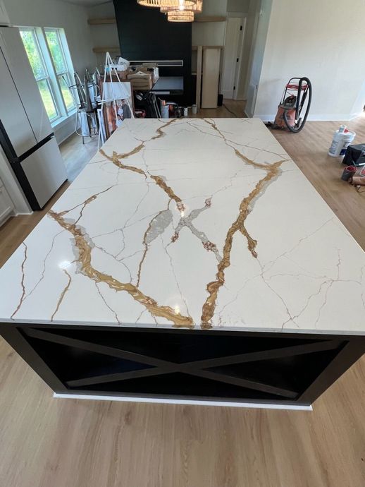 A large white marble counter top is in a kitchen.