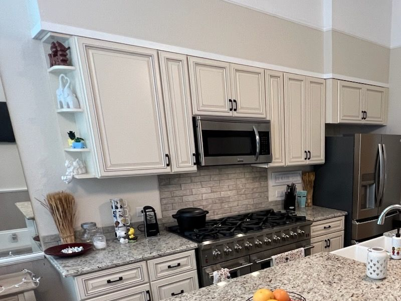 Modern kitchen with cream cabinets, stainless appliances, and a gas stove with stone backsplash