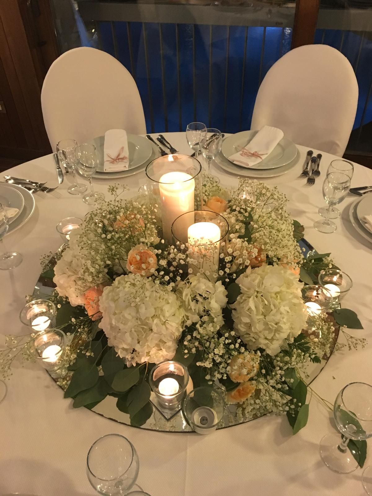 Tavolo per il ricevimento di nozze con centrotavola floreale e candele.