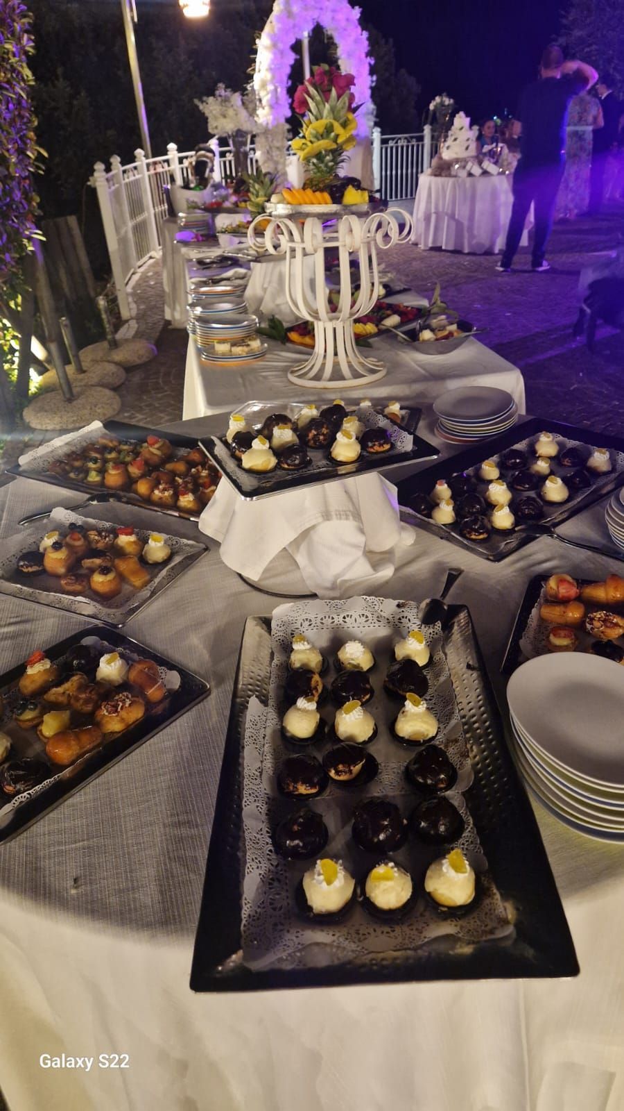 Tavolo con frutta tovaglie bianche e un arco decorativo sullo sfondo.