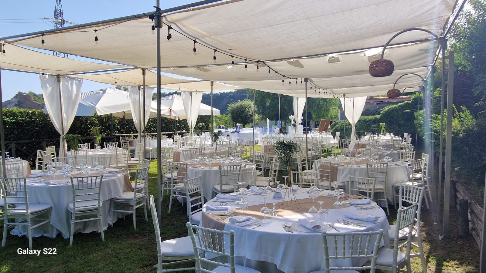 Allestimento per ricevimento di nozze all'aperto con tavoli, sedie e tende 