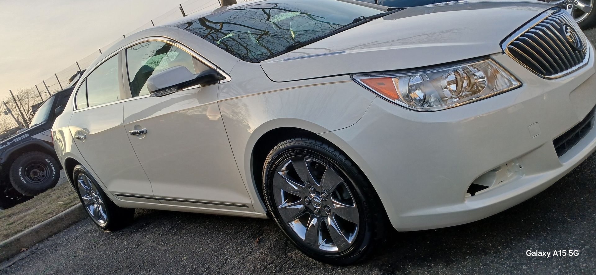 White Buick car with chrome wheels, parked outdoors.