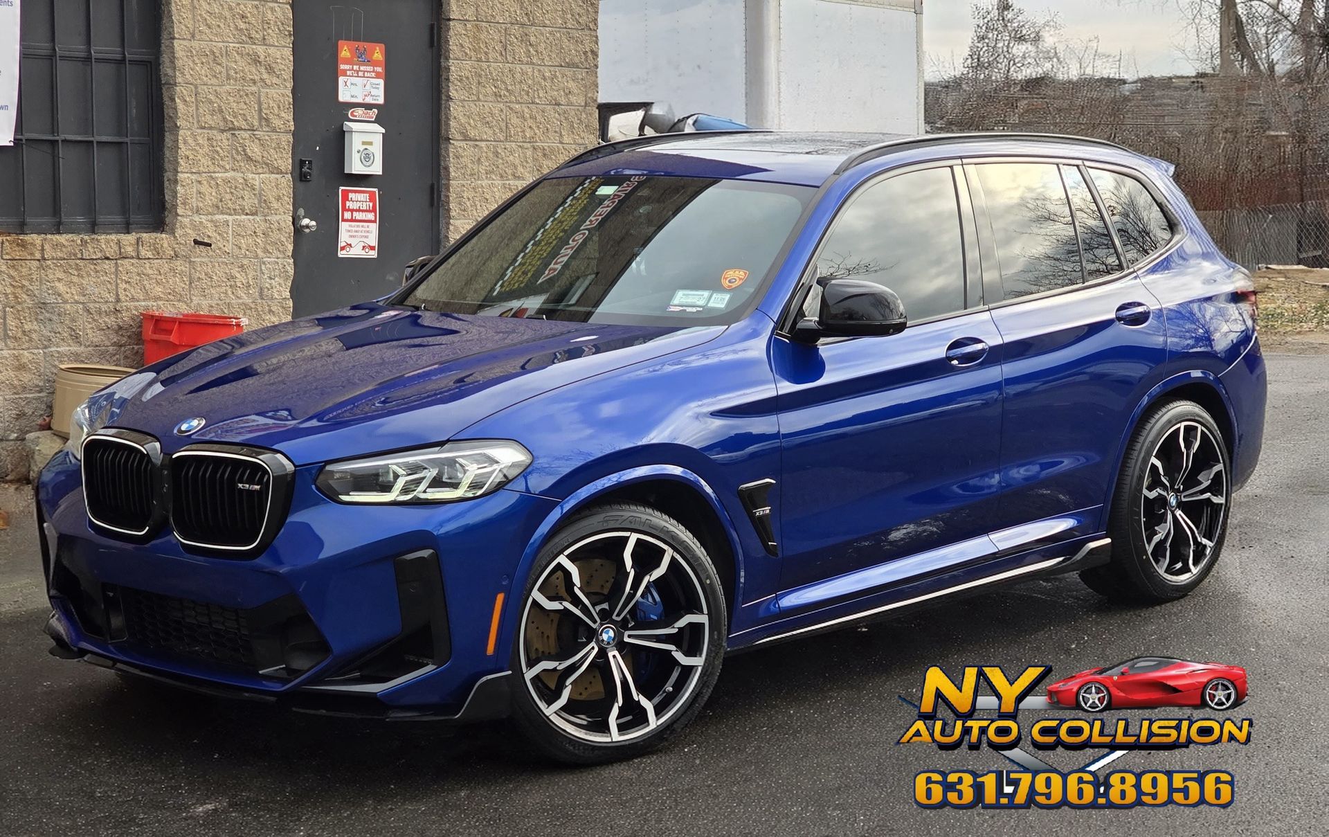 Blue BMW X3 M SUV parked in front of a building; NY Auto Collision logo is visible.