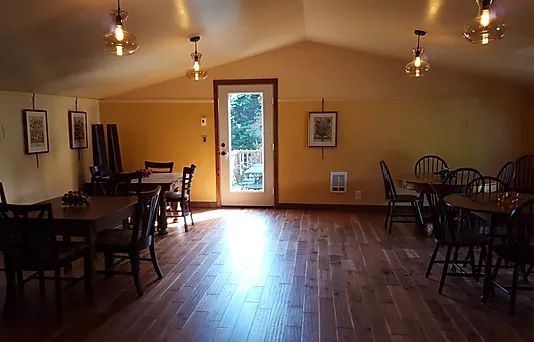 A large room with wooden floors and tables and chairs.