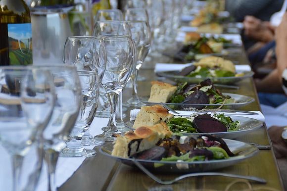 A long table topped with plates of food and wine glasses.