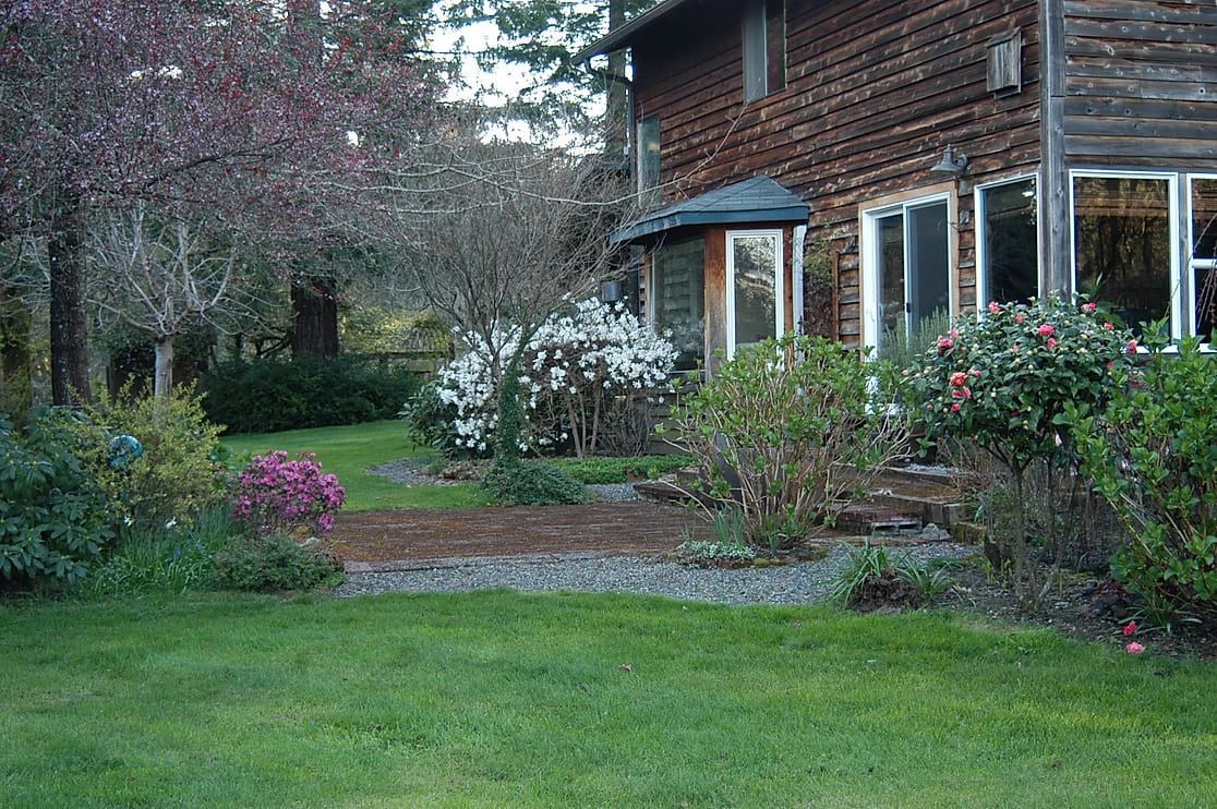 A large wooden house with a large lawn in front of it.