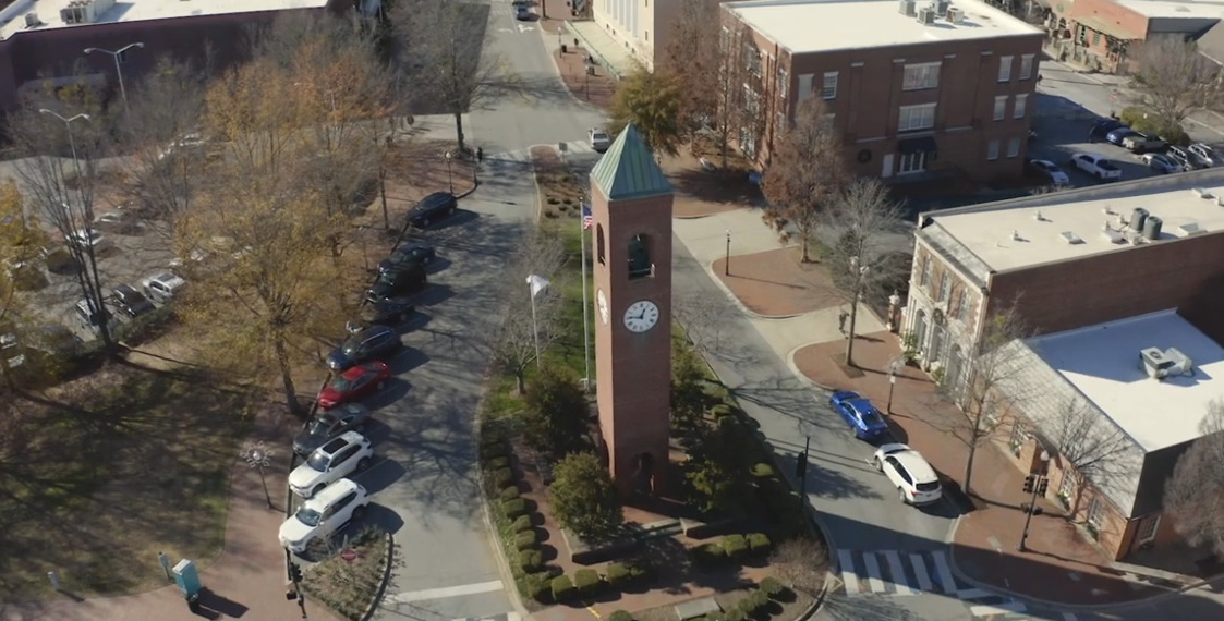 An aerial view of a city with a clock tower in the middle of it.