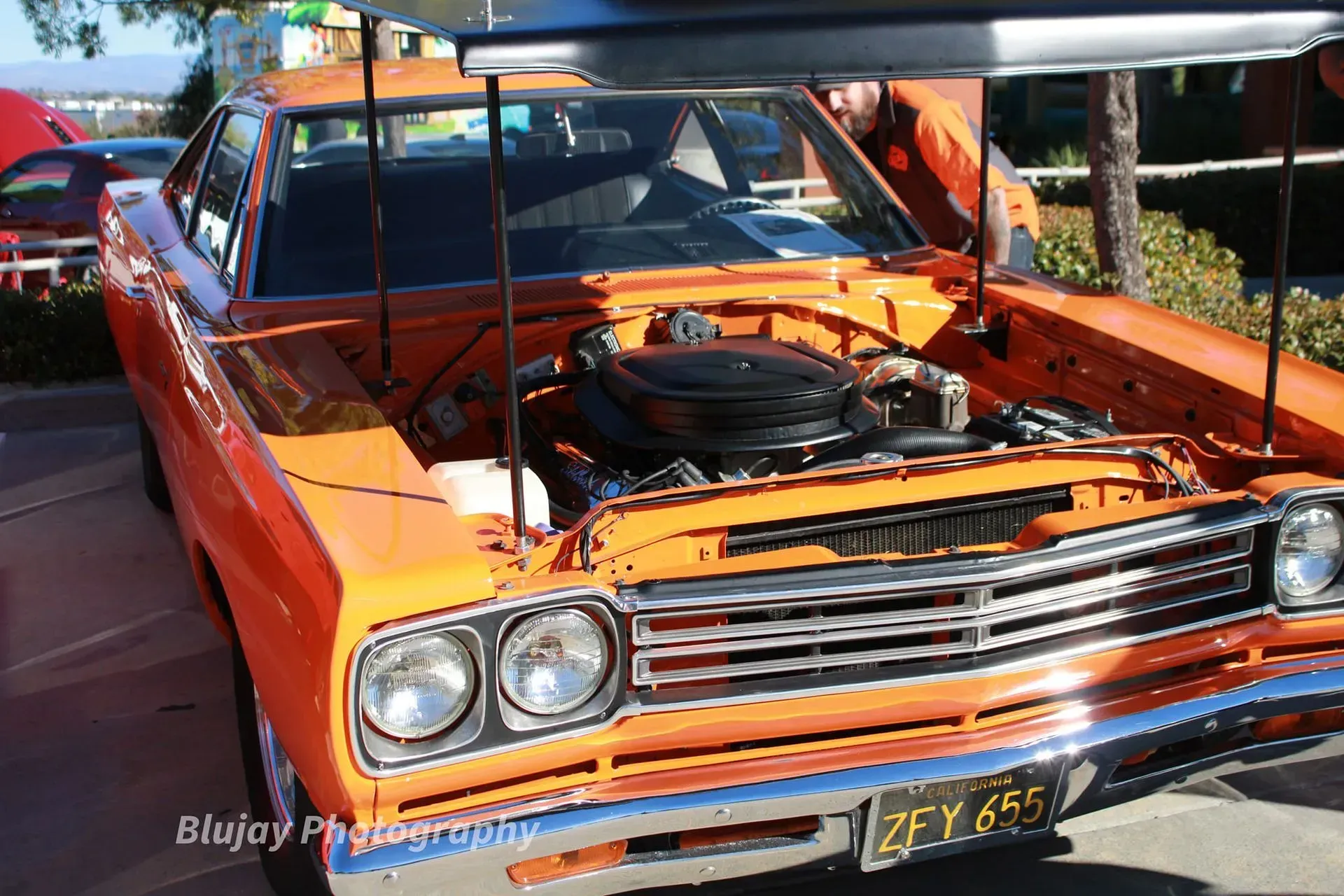 An orange car with the hood open has a license plate that says 2fy685