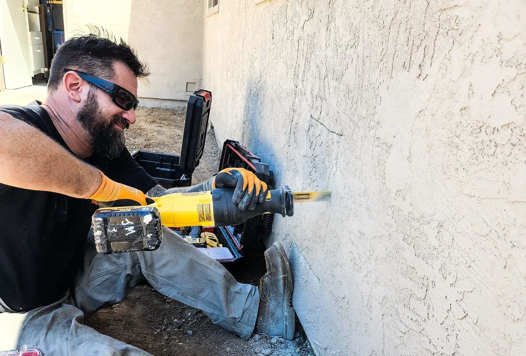 A man is using a hammer to drill a hole in a wall.