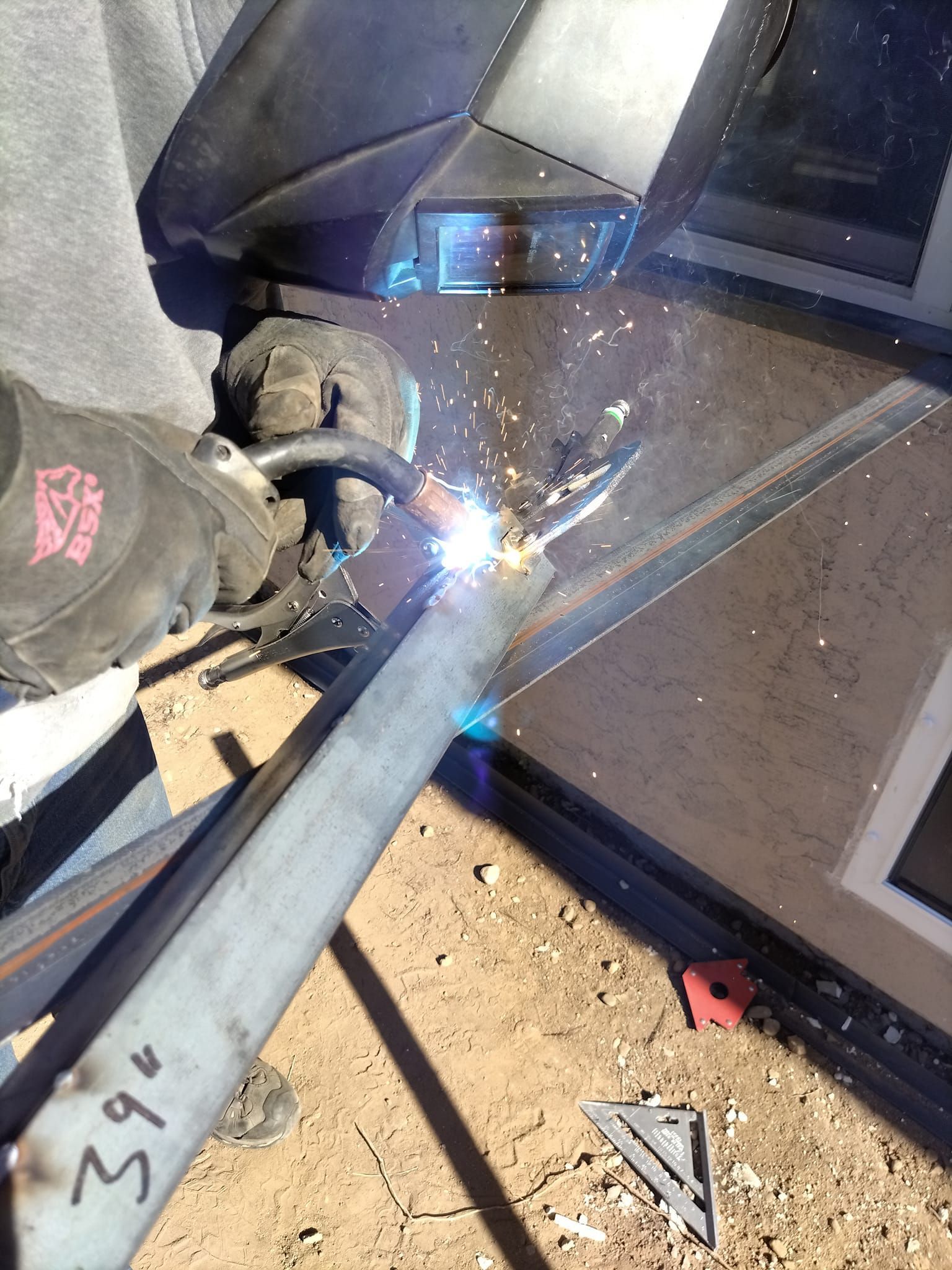 Welder welding metal outdoors. Sparks fly from the contact point.
