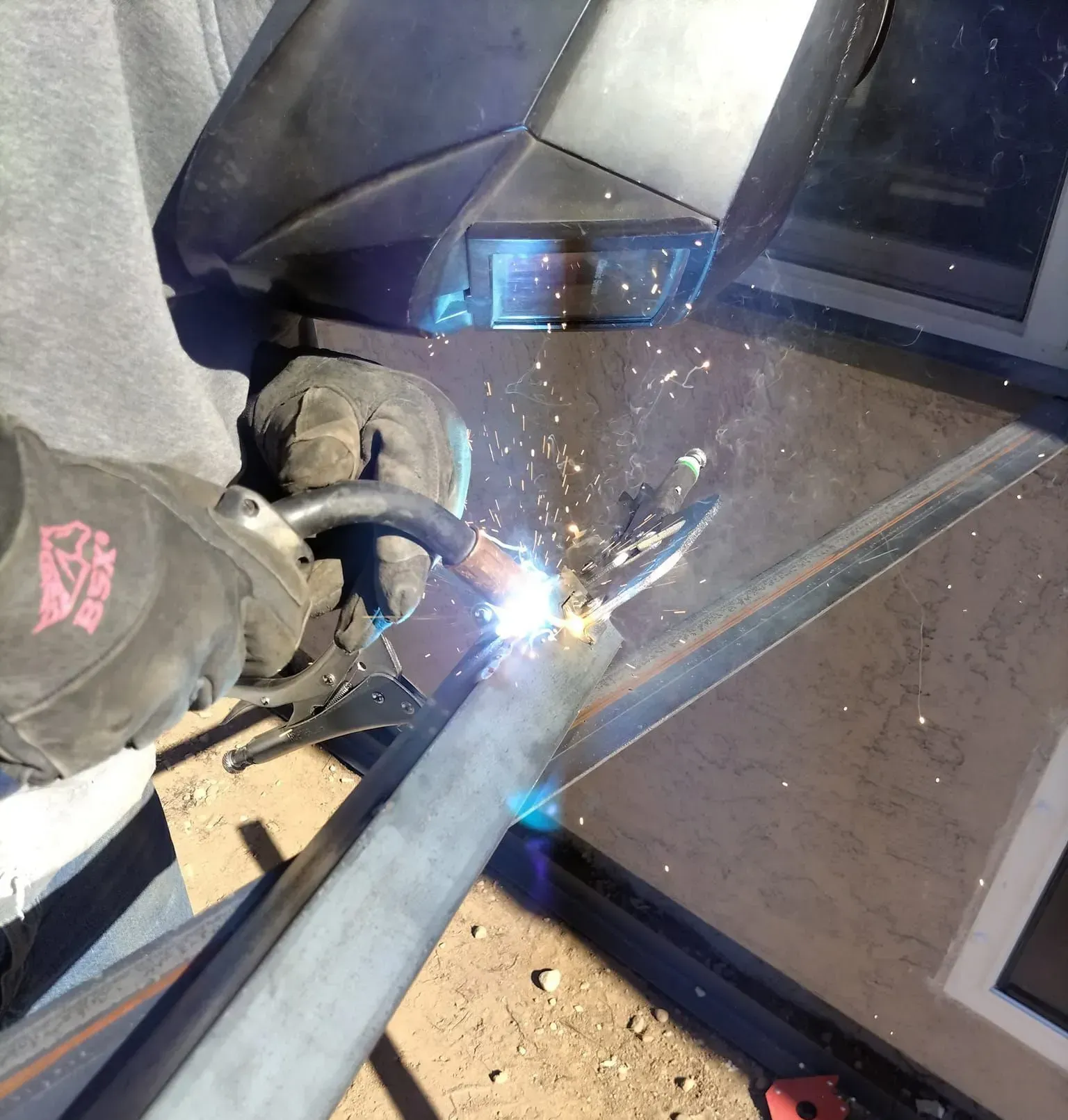 A person wearing a pair of welding gloves is welding a piece of metal
