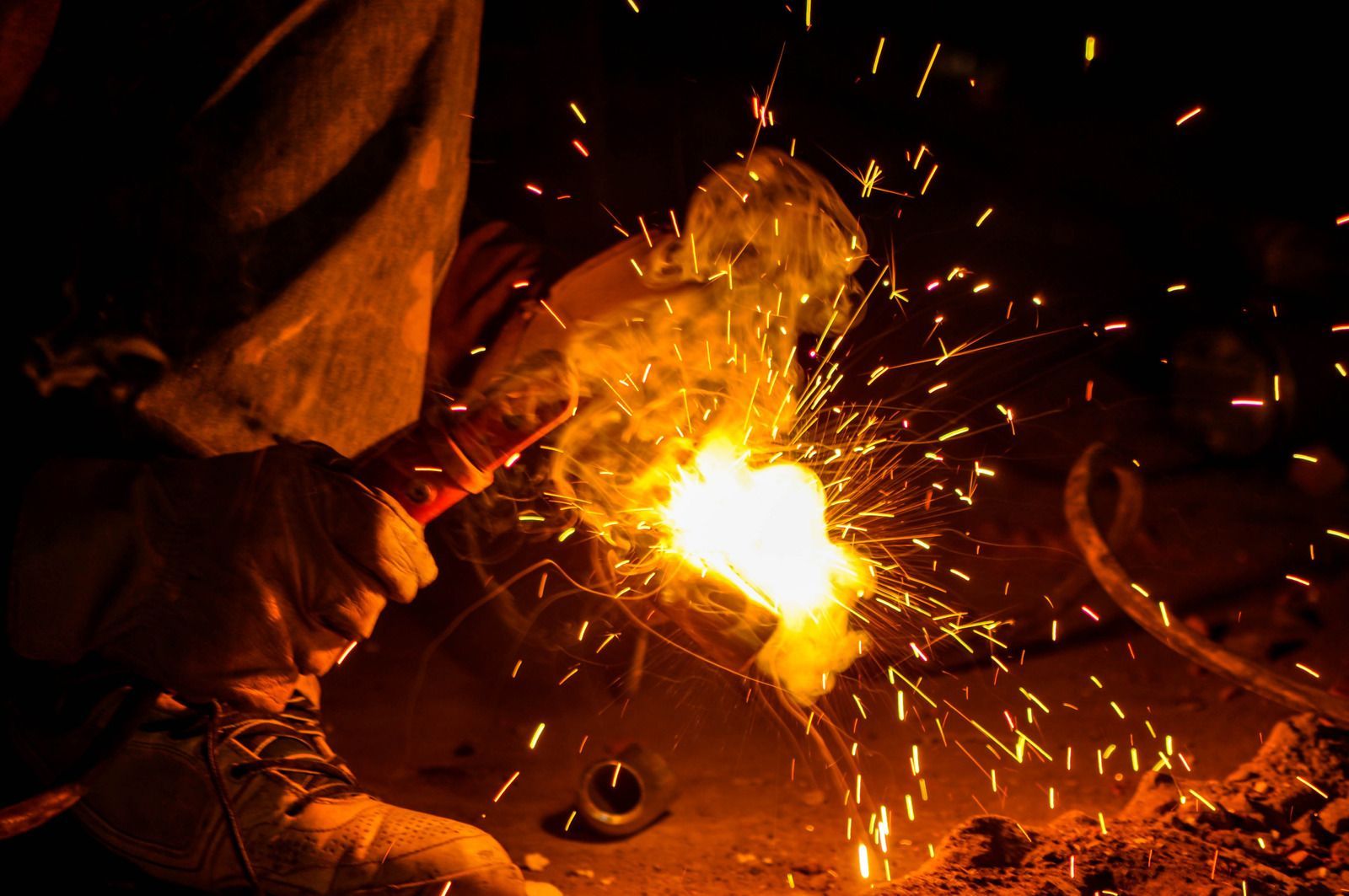 A person is welding a piece of metal with sparks coming out of it.