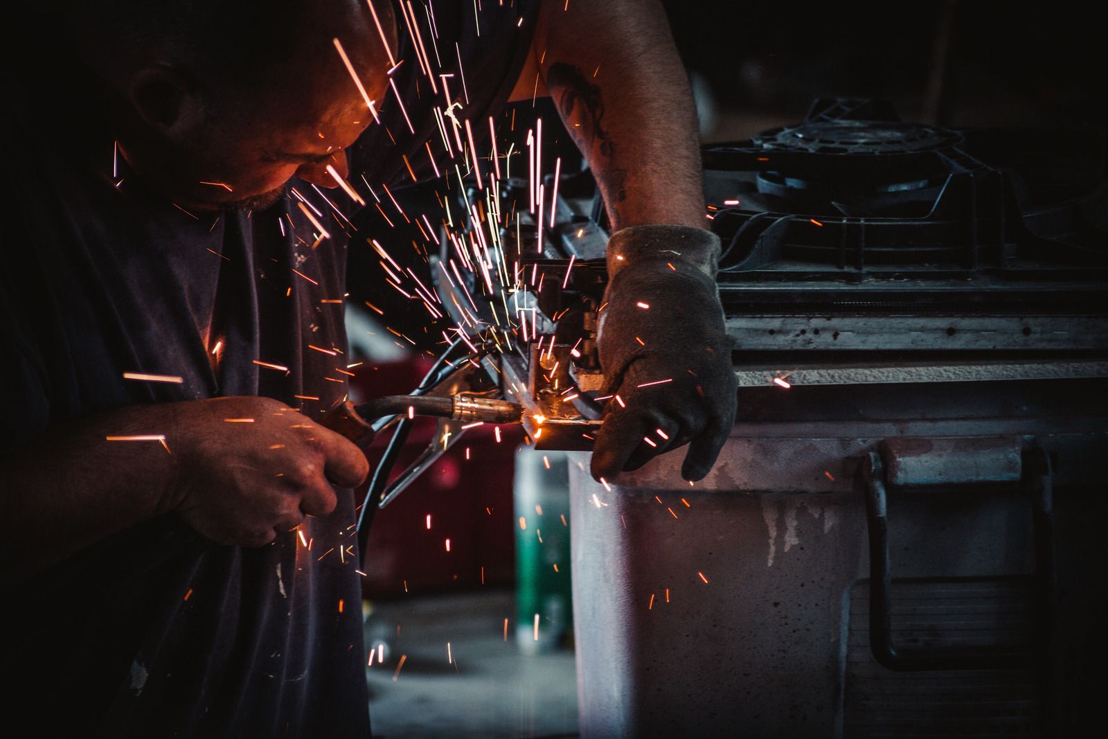 A man is grinding a piece of metal with sparks coming out of it.
