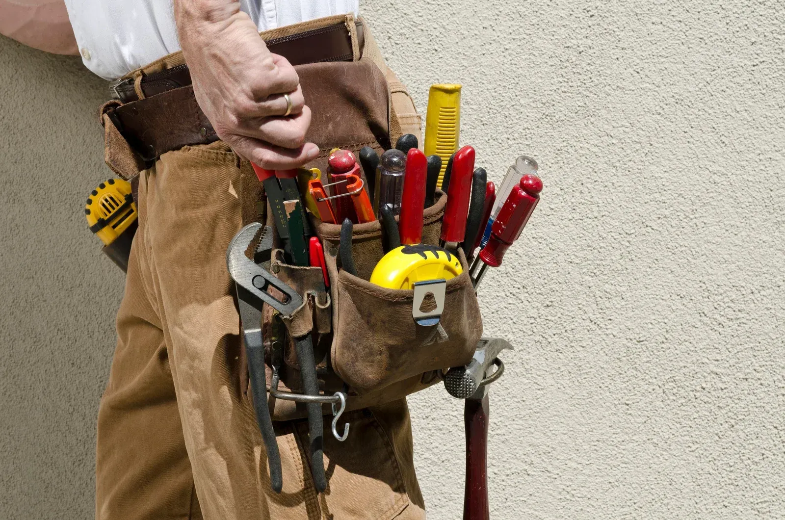 A man is wearing a tool belt filled with tools.